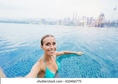 Vacation And Technology. Pretty Young Woman Taking Selfie While Swimming In Roof Top Pool With Beautiful City View.