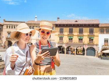 vacation and travel concept - two beautiful girls toursits looking into tablet pc in the old city in Europe
