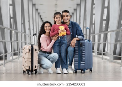 Vacation Trip. Portrait Of Happy Young Arab Family Posing At Airport, Parents And Little Daughter Standing With Suitcases At Terminal While Waiting For Flight Boarding, Enjoying Travelling Together