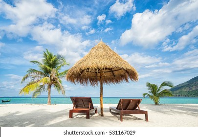 Vacation in tropical countries. Beach chairs, umbrella and palms on the beach. 