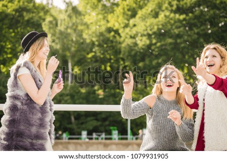 Vacations joy, friendship concept. Women friends having fun blowing soap bubbles outdoor.
