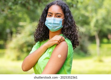 Vaccinated Girl Teenager Teen Mixed Race Biracial African American Female Young Woman Wearing Face Mask In Coronavirus COVID-19 Pandemic Showing Vaccine Band Aid