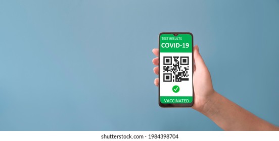 Vaccinated person holding mobile phone with digital health passport for travel during covid-19 pandemic. Green certificate - Shutterstock ID 1984398704