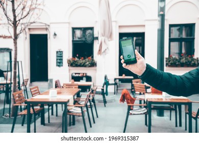 Vaccinated person using immunization certificate on smartphone at the restaurant or terrace. 