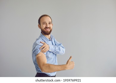 Vaccination Campaign. Adult Caucasian Business Man Office Worker Showing Medical Adhesive Patch On Arm After Receiving COVID Vaccine Gesturing Thumbs Up And Smiling To Camera Expressing Studio Shot