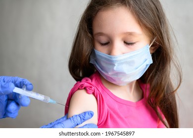 Vaccination Of Child From COVID-19, Monkeypox, Tetanus Or Flu, Cute Little Girl In Mask Closes Eyes During Injection. Needle For Jab To Kid In School. Concept Of Corona Virus, Risk, Health And Shot.