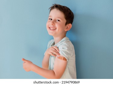 Vaccination Concept. Caucasian Boy In A Blue T-shirt With Band Aid Thumbs Up On A Blue Background With Copy Space