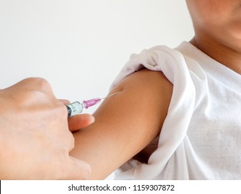 Vaccination concept. Female doctor vaccinating little Asian boy in clinic isolated on white background.
