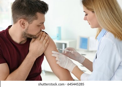 Vaccination concept. Female doctor vaccinating young man - Powered by Shutterstock