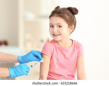 Vaccination concept. Female doctor vaccinating cute little girl in clinic
