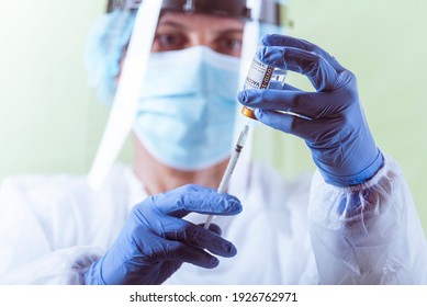 Vaccination, doctor in protective clothes with syringe and ampule - Shutterstock ID 1926762971