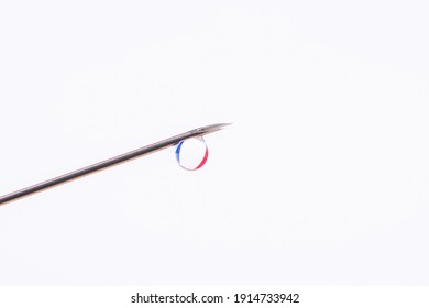 Vaccination In France. Needle With A Small Drop Against Flag Of France In The Background. Photo With Copy Space