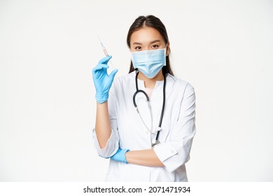 Vaccination and healthcare concept. Asian female doctor, nurse in medical face mask and gloves holding syringe with vaccine, white background - Powered by Shutterstock