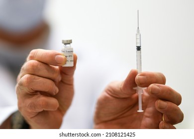 Vaccination Illustration, A General Practitioner In His Office, holds A Vial (BioNTech, Pfizer) And A Syringe With The Covid-19 Vaccine, Before Vaccinate A Patient.