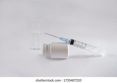 Vaccination and immunity improvement. Medical syringe with vaccine, glass ampules and a bottle with vitamins on white background.  