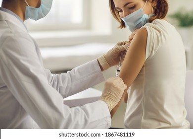 Vaccination, Immunization, Disease Prevention Concept. Patient Getting Covid-19 Vaccine At Doctor's Office. Cropped Shot Of Professional Nurse In Medical Face Mask Giving Flu Injection To Young Woman