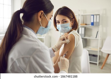 Вакцинация, иммунизация, концепция профилактики заболеваний. Женщина в медицинской маске получает вакцину от Covid-19 или гриппа в больнице. Профессиональная медсестра или врач, делающий противовирусную инъекцию пациенту