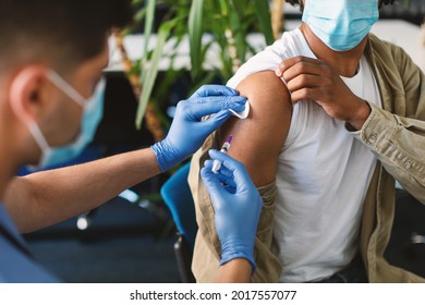 Vaccination, Immunization, Disease Prevention Concept. Closeup Of Black Man In Face Mask Getting Covid Or Flu Vaccine At The Hospital. Professional Male Doctor Giving Antiviral Injection To Patient