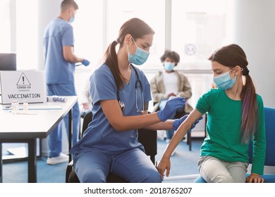 Vaccination, Immunization, Disease Prevention Concept. Young girl in face mask getting Covid or flu vaccine at the health centre. Professional female doctor giving antiviral injection to patient