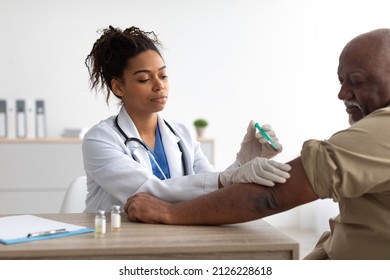 Vaccination, Immunization, Disease Prevention Concept. Mature Black Man Getting Covid-19 Or Flu Vaccine At The Hospital. Professional Female Doctor Giving Antiviral Jab To Elderly Citizen