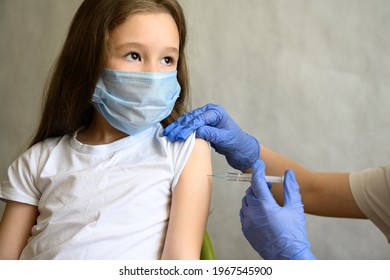 Vaccination Of Little Girl From COVID-19 Or Smallpox, Cute Child In Mask Getting Vaccine. Doctor Makes Jab From Coronavirus To Kid In School. Concept Of Corona And Monkeypox, Injection, Shot And Flu.