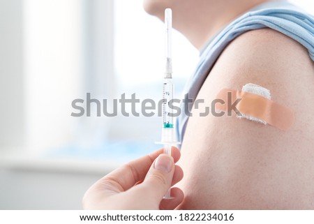 Vaccination of man, adult in doctor's office. Beige adhesive plaster,tape gauze napkin.Syringe with vaccine for covid-19 coronavirus,flu,infectious diseases. njection.Clinical trials for human,child.