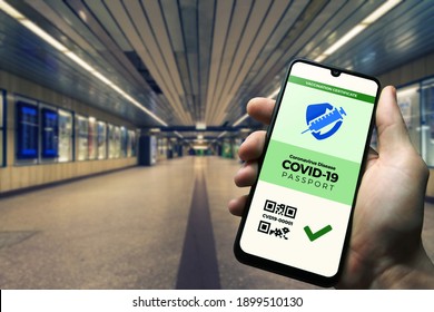 Vaccination passport for COVID-19 displayed on smartphone held in male's hand at train station. Vaccination, disease immunity passport, health and surveillance concepts - Powered by Shutterstock