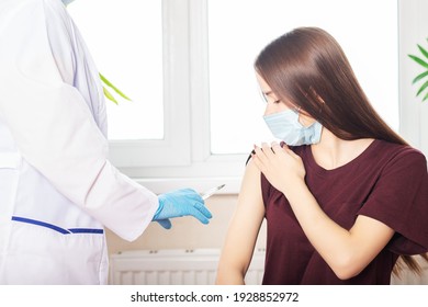 Vaccination of teenagers from covid-19, the doctor gives a shot of the vaccine to a girl in a medical hospital
