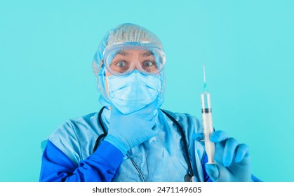 Vaccination and treatment. Serious doctor in goggles, surgical cap and face mask holds syringe with vaccine. Male nurse or physician in rubber gloves preparing for injection. Healthcare and medicine - Powered by Shutterstock