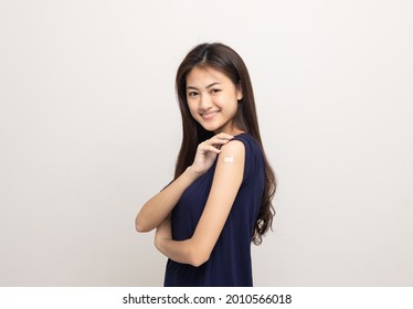 Vaccination. Young Beautiful Asian Woman Getting A Vaccine Protection The Coronavirus. Smiling Happy Female Showing Arm With Bandage After Receiving Vaccination. On Isolated White Background.
