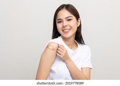 Vaccination. Young Beautiful Asian Woman Getting A Vaccine Protection The Coronavirus. Smiling Happy Female Showing Arm After Receiving Vaccination. On Isolated White Background.