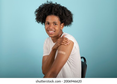 Vaccination Of A Young Latino Man Showing His Arm After Coronavirus Vaccination On A Blue Background.