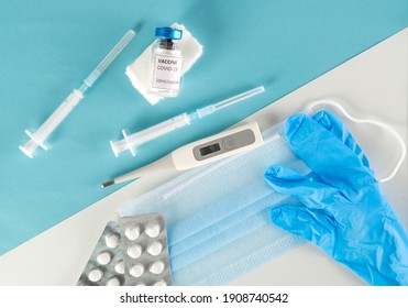 Vaccine Against The Coronavirus And Pandemic Concept. Syringes For Vaccination With Vaccine Vial Against Protective Face Masks, Pills And Gloves. Back To Normal Life. No Quarantine, A New Life Begins.