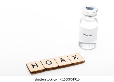 Vaccine Concept Showing A Medical Vial With A Vaccine Label On A White Background Along With A Sign Reading Hoax