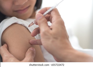 Vaccine Healthcare Concept. Image Of Strong Happy Healthy Asia Kid Girl Smiling Getting Vaccination With Doctor Pediatrician's Hand Holding Medical Syringe In Hospital.