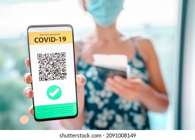 Vaccine Passport On Mobile Phone App Screen Woman Tourist Showing Vaccination Proof For COVID-19 At Airport For Vacation Travel Flight During Coronavirus Pandemic.