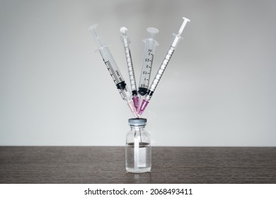 A vaccine vial with 4 syringes. A fourth dose Covid-19 vaccine booster shot concept. - Shutterstock ID 2068493411