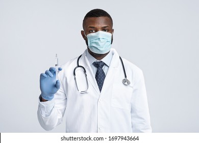 Vacination During Quarantine. Black Male Doctor In Face Mask Holding An Injection Over White Background