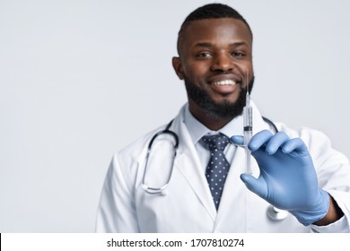 Vacination During Quarantine. Smiling African Male Doctor Holding An Injection Over White Background, Copy Space