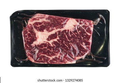 Vacuum Black Plastic Pack With Fresh Beef Steak Isolated On White Background. Raw Fatty Meat Packed Without Label Top View