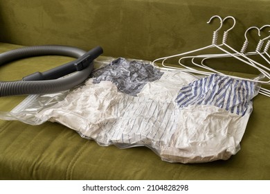 Vacuum pack full of apparel,hangers and vacuum hose on the sofa at home