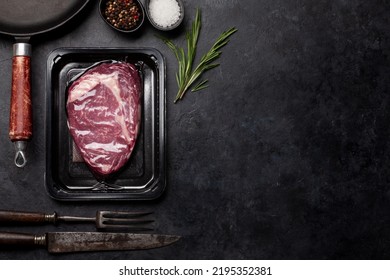 Vacuum packed beef steak. Ribeye steak and cooking utensils. Top view flat lay with copy space - Shutterstock ID 2195352381