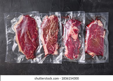 Vacuum packed organic raw beef alternative cuts: top blade, rump, picanha, chuck roll steaks, over black textured background, top view