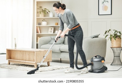 Vacuuming, cleaning and housework done by a mother, house wife or girlfriend using a vacuum cleaner. Stay at home mom, maid or housekeeper doing household chores and tidying in a modern living room - Shutterstock ID 2190805355