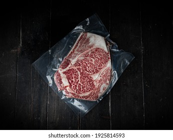 Vacuum-packed piece of Wagyu beef steak. Raw beef steak on a wooden background in a butcher shop. Japanese premium product.