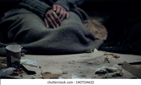 Vagabond covered with dirty blanket sitting on carton, living on street, refugee