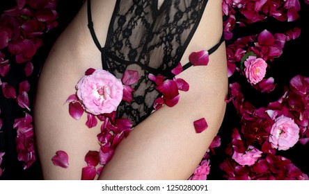 Vagina concept. Erotic black lingerie, lace underwear and pink flowers. Romantic evening, a gift for Christmas, waiting for Valentine's Day. Hot girl with a sensual body. Seductive female hips