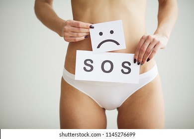 Vaginal or urinary infection and problems concept. Young woman holds paper with SOS above crotch.