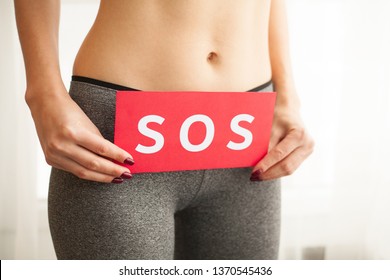 Vaginal or urinary infection and problems concept. Young woman holds paper with SOS above crotch
