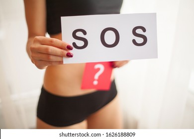 Vaginal or urinary infection and problems concept. Young woman holds paper with Sos above crotch
